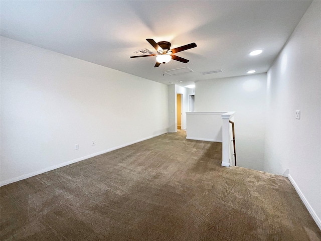 unfurnished room with a ceiling fan, dark colored carpet, and baseboards