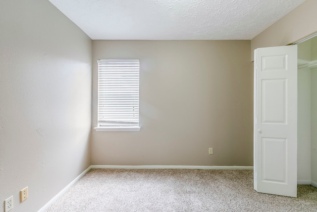 empty room with a textured ceiling, carpet, and baseboards