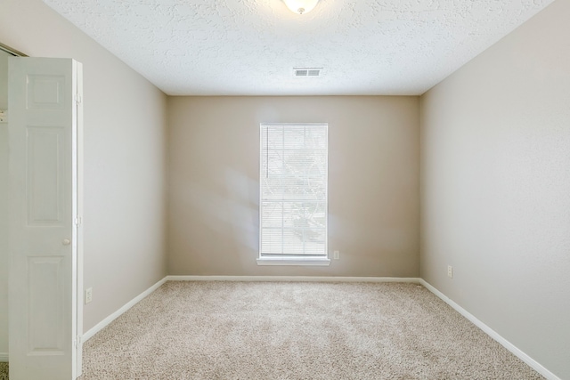 empty room with baseboards, a textured ceiling, visible vents, and carpet flooring