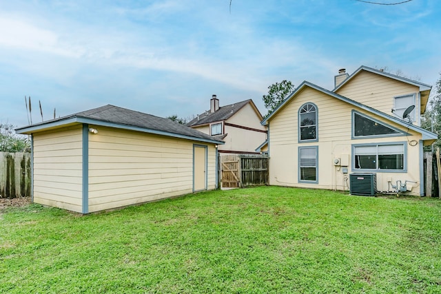 back of property with cooling unit, a lawn, and fence