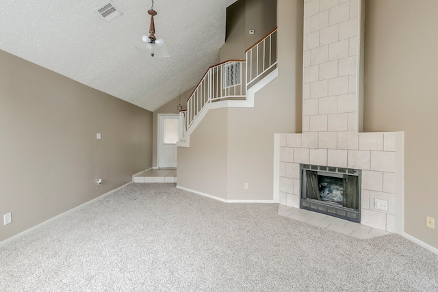 unfurnished living room featuring a textured ceiling, a fireplace, visible vents, stairs, and carpet