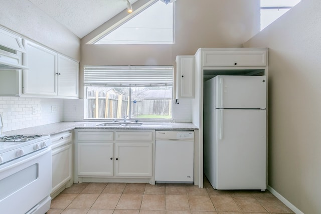 kitchen featuring white appliances, light tile patterned floors, white cabinets, decorative backsplash, and lofted ceiling