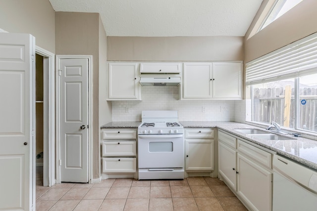 kitchen featuring white appliances, white cabinetry, under cabinet range hood, and light tile patterned floors