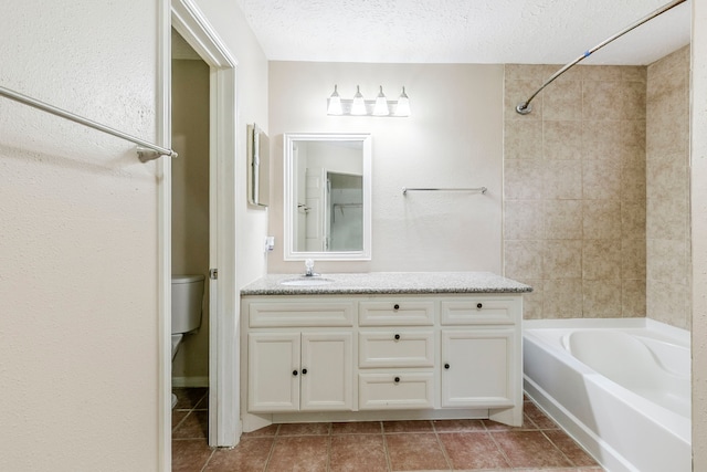 bathroom with toilet, tile patterned floors, a textured ceiling, vanity, and washtub / shower combination