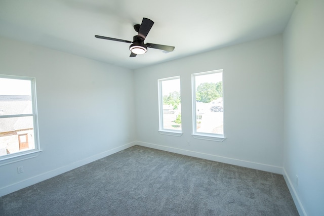 carpeted empty room featuring a ceiling fan, baseboards, and a wealth of natural light