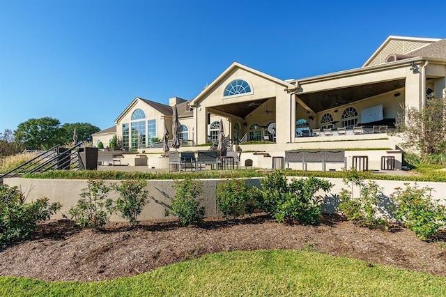 rear view of house with a fenced front yard, a ceiling fan, and stucco siding