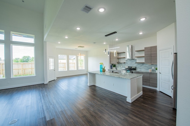 kitchen with light stone counters, exhaust hood, visible vents, appliances with stainless steel finishes, and open shelves