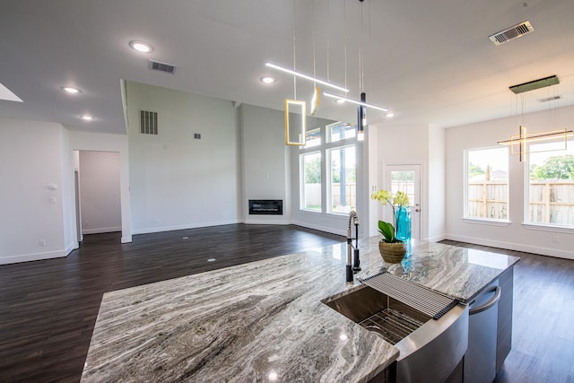 kitchen with light stone counters, visible vents, and pendant lighting