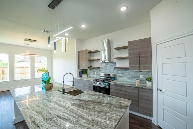 kitchen featuring a sink, wall chimney range hood, open shelves, gas stove, and decorative light fixtures