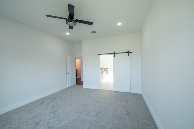 unfurnished bedroom featuring a barn door, recessed lighting, carpet flooring, visible vents, and baseboards