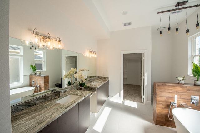 full bathroom featuring a freestanding tub, a sink, two vanities, visible vents, and a walk in closet