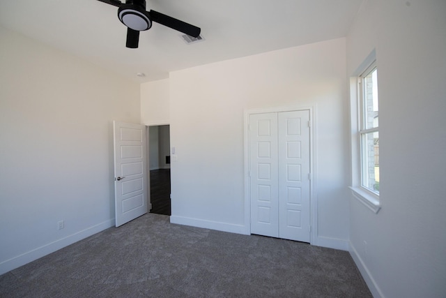 unfurnished bedroom with multiple windows, baseboards, and dark colored carpet