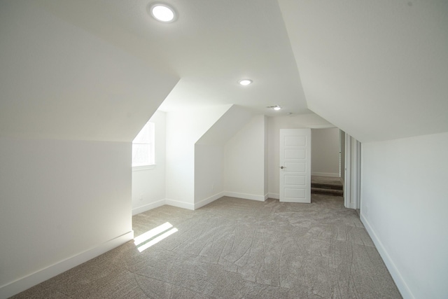 bonus room featuring lofted ceiling, light carpet, and baseboards