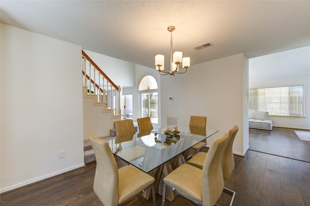 dining space with dark wood finished floors, visible vents, an inviting chandelier, a textured ceiling, and stairs