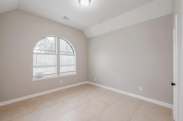 empty room featuring visible vents, vaulted ceiling, baseboards, and light tile patterned floors