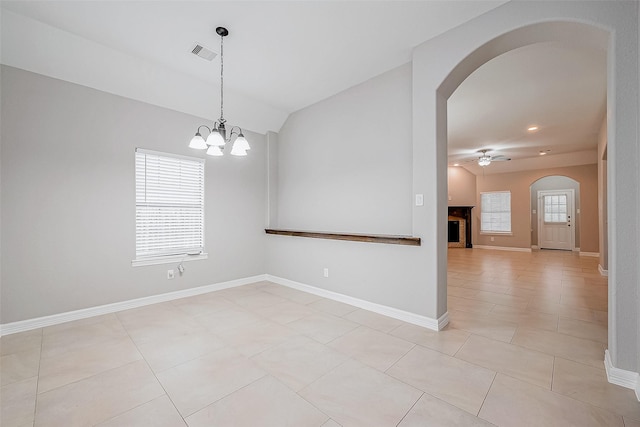 empty room featuring arched walkways, ceiling fan with notable chandelier, plenty of natural light, and visible vents