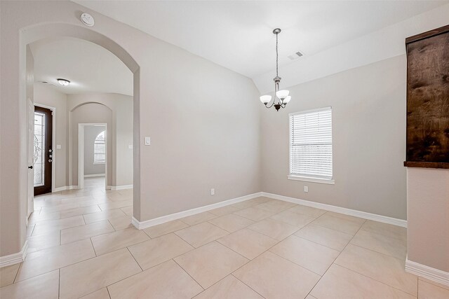 spare room featuring vaulted ceiling, baseboards, and light tile patterned floors