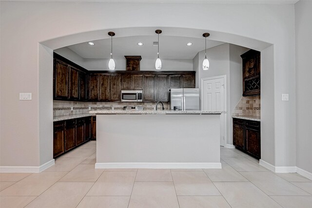 kitchen featuring stainless steel appliances, pendant lighting, an island with sink, and dark brown cabinets