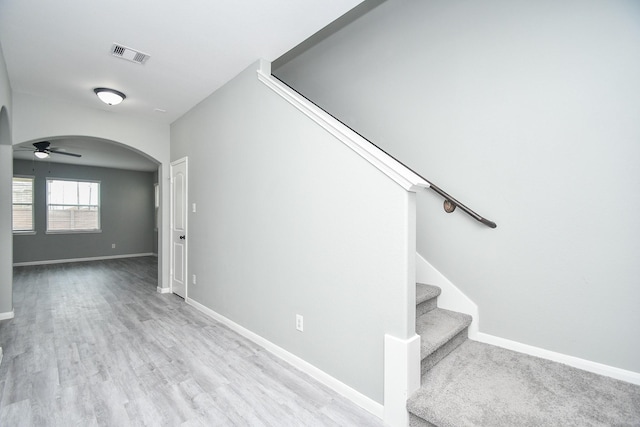 staircase with baseboards, visible vents, arched walkways, ceiling fan, and wood finished floors