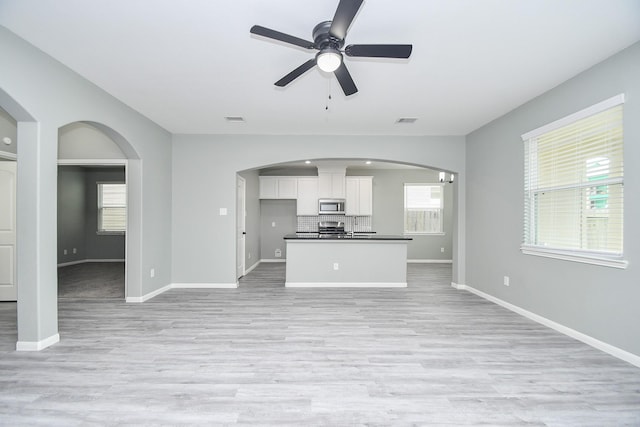 kitchen featuring dark countertops, white cabinets, stainless steel microwave, and arched walkways