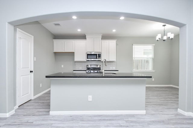 kitchen with appliances with stainless steel finishes, an island with sink, visible vents, and white cabinets