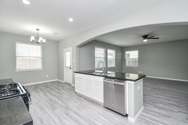 kitchen featuring arched walkways, decorative light fixtures, white cabinets, a sink, and dishwasher