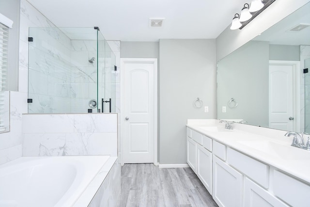 bathroom with a stall shower, visible vents, a sink, and a garden tub