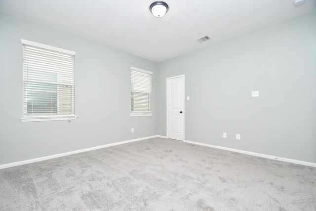 empty room featuring carpet, visible vents, and baseboards