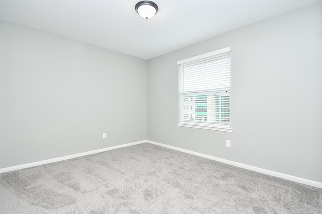 carpeted empty room featuring baseboards