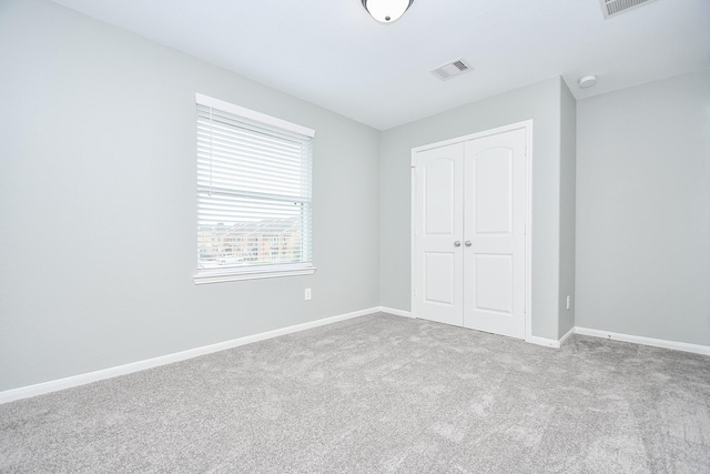 unfurnished bedroom with light colored carpet, a closet, visible vents, and baseboards