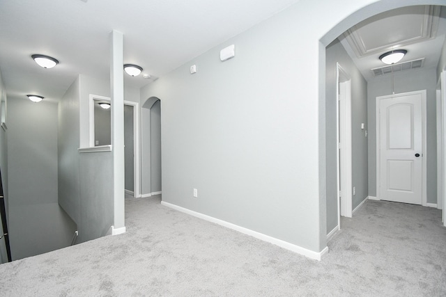 spare room featuring arched walkways, light colored carpet, visible vents, and baseboards