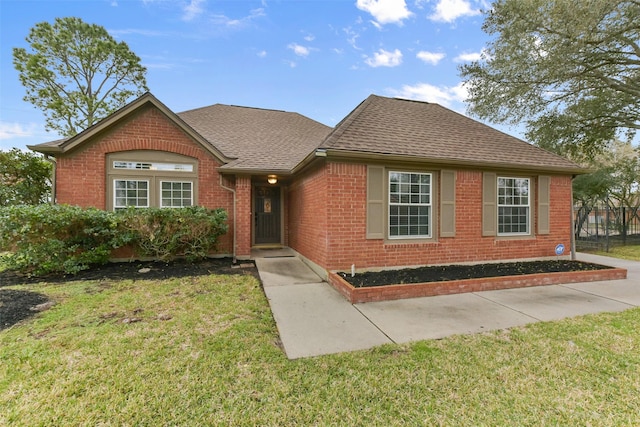 single story home with a shingled roof, a front lawn, and brick siding