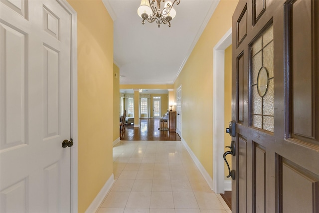 entrance foyer featuring ornamental molding, a notable chandelier, baseboards, and light tile patterned floors