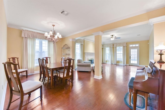 dining room featuring a glass covered fireplace, a healthy amount of sunlight, visible vents, and wood finished floors