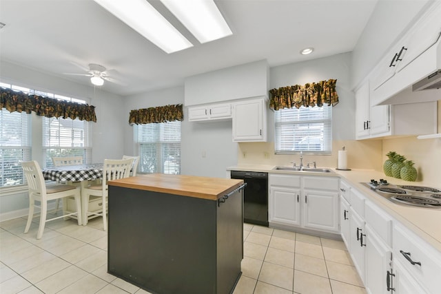 kitchen featuring black dishwasher, wood counters, a center island, white cabinetry, and a sink