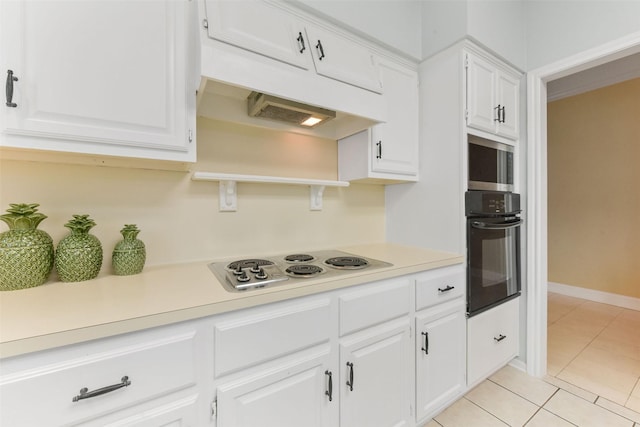 kitchen featuring light tile patterned floors, white cabinets, oven, white cooktop, and light countertops