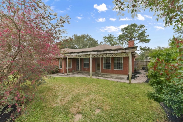 rear view of property with a patio area, a lawn, a chimney, and fence