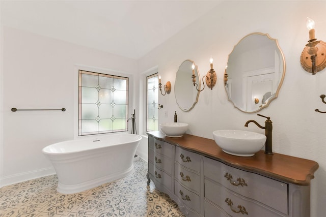 full bathroom with a soaking tub, double vanity, a sink, and tile patterned floors