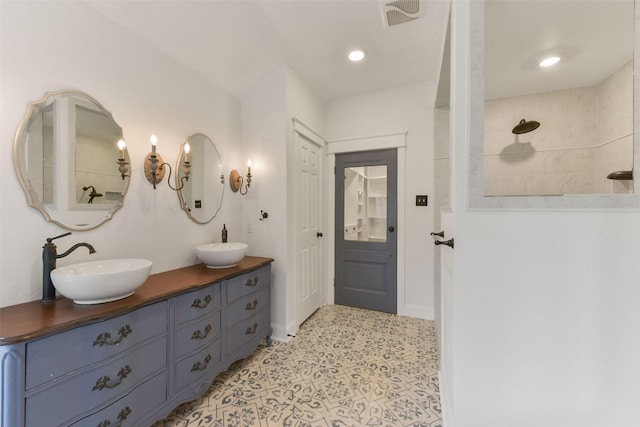 full bath featuring double vanity, baseboards, visible vents, and a sink