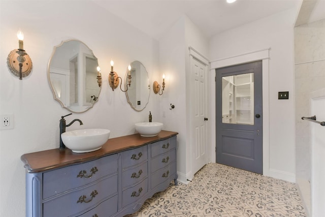 bathroom with a sink, baseboards, and double vanity