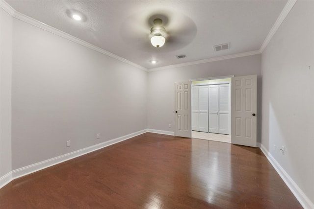 unfurnished bedroom featuring dark wood-style flooring, visible vents, crown molding, and baseboards