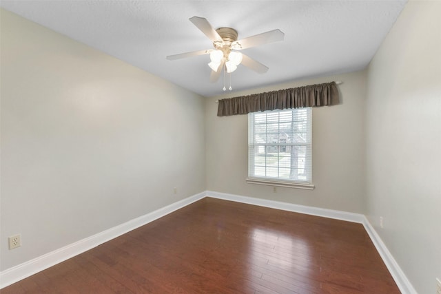 spare room featuring dark wood-type flooring, ceiling fan, and baseboards