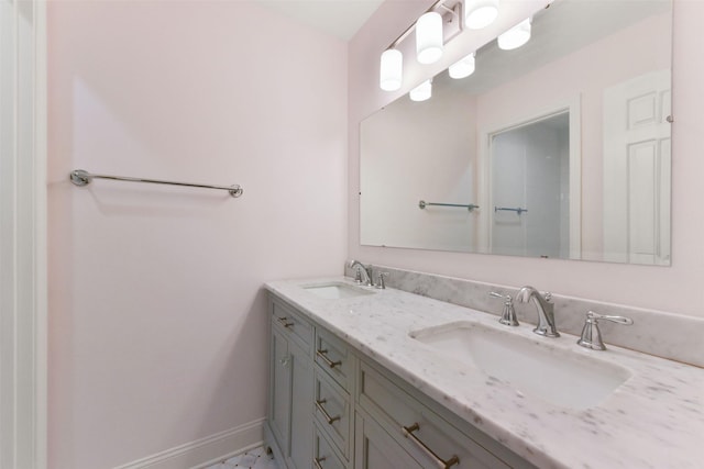 bathroom with a sink, baseboards, and double vanity