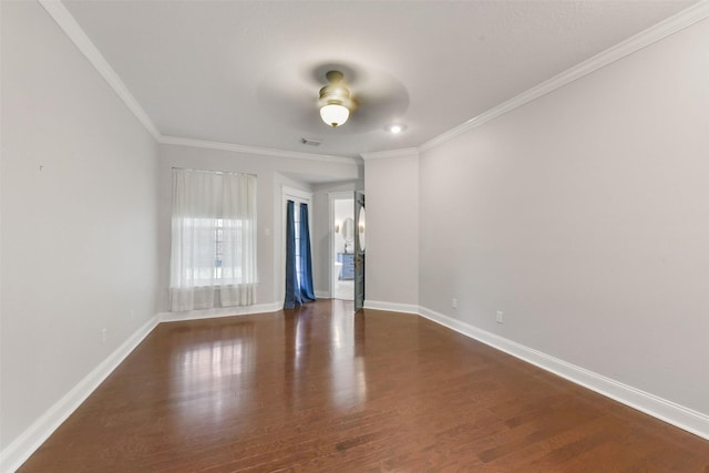 empty room featuring dark wood-style flooring, visible vents, crown molding, and baseboards