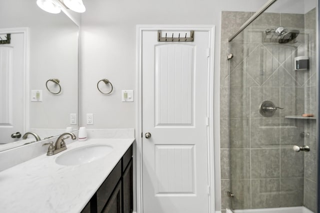 full bathroom featuring tiled shower and vanity