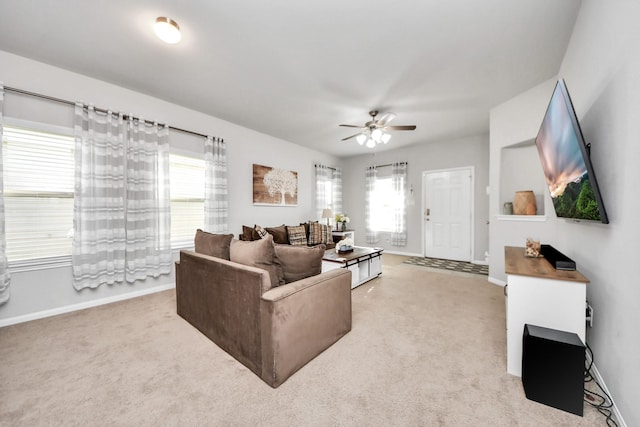 living room with a ceiling fan, light colored carpet, and baseboards