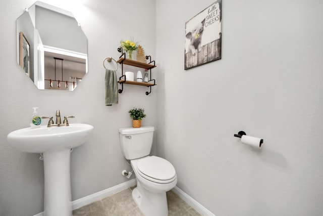 half bath with tile patterned flooring, toilet, and baseboards