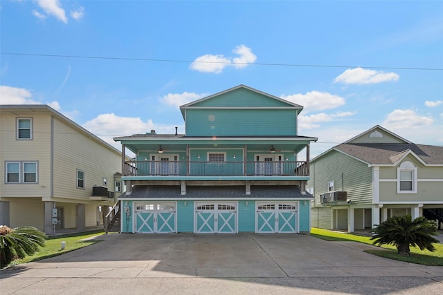 coastal home featuring a balcony, driveway, a garage, and central AC unit