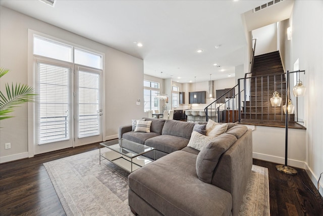 living area featuring stairway, baseboards, visible vents, and dark wood finished floors