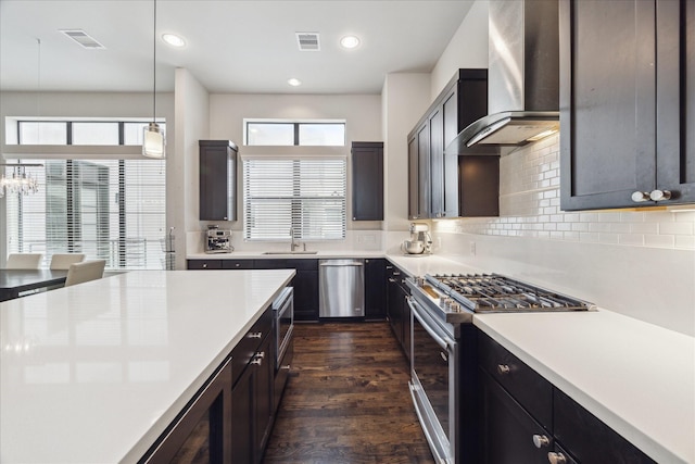 kitchen featuring visible vents, wall chimney exhaust hood, decorative light fixtures, light countertops, and stainless steel appliances